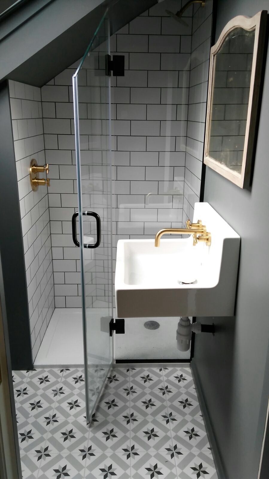 Compact loft shower room with patterned floor and brass fittings